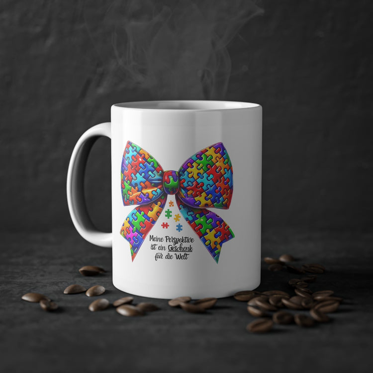 Weiße Keramiktasse mit bunter Puzzle-Schleife in Regenbogenfarben und Schriftzug "Meine Perspektive ist ein Geschenk für die Welt" - Symbol für Inklusion & Vielfalt