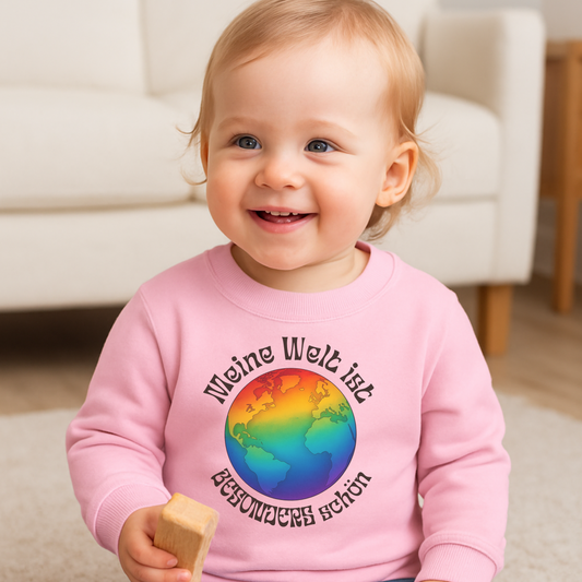 Kleinkind trägt rosa farbenen Pullover mit Bunte Wetkugel- Aufdruvk und dem Schriftzug "Meine Welt ist besonders schön" Ein Ztatement für Inklusion und Vielfalt