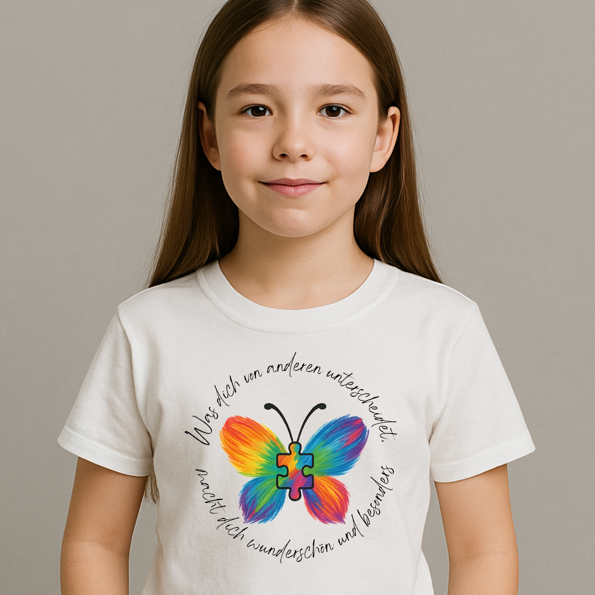 Mädchen trägt weißes Shirt mit einem bunten Schmetterling mit Puzzle-Herz. Dazu der Schriftzug- Was dich von anderen unterscheidet macht dich wunderschön und besonders. Ein Zeichen für Vielfalt und Akzeptanz