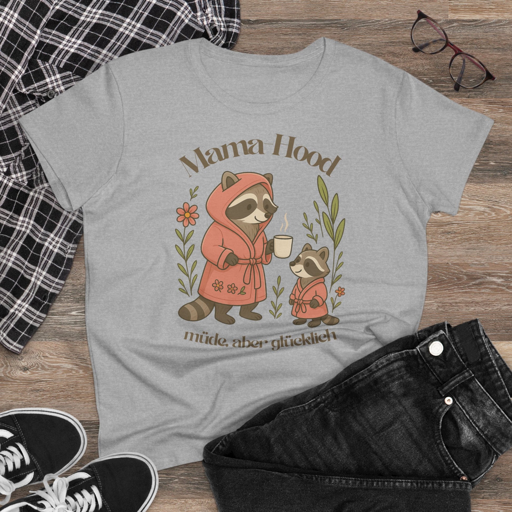 Graues Mama-T-Shirt mit Waschbär-Motiv und Zitat „Müde, aber glücklich“. Stylishes Statement-Shirt für Mütter, aus weicher Baumwolle gefertigt.