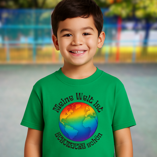Junge trägt grünes Kinder T-Shirt ‚Meine Welt ist besonders schön‘ mit bunter Weltkugel. Statement für Vielfalt, Inklusion & Selbstvertrauen.